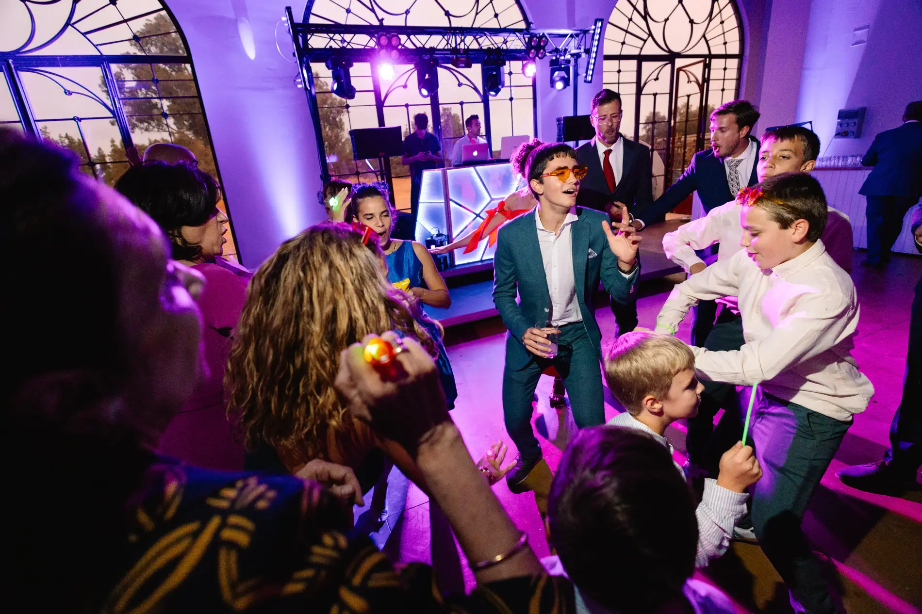 Niños e invitados bailan en el salón con luces violetas, en Casa Colorada, Badajoz
