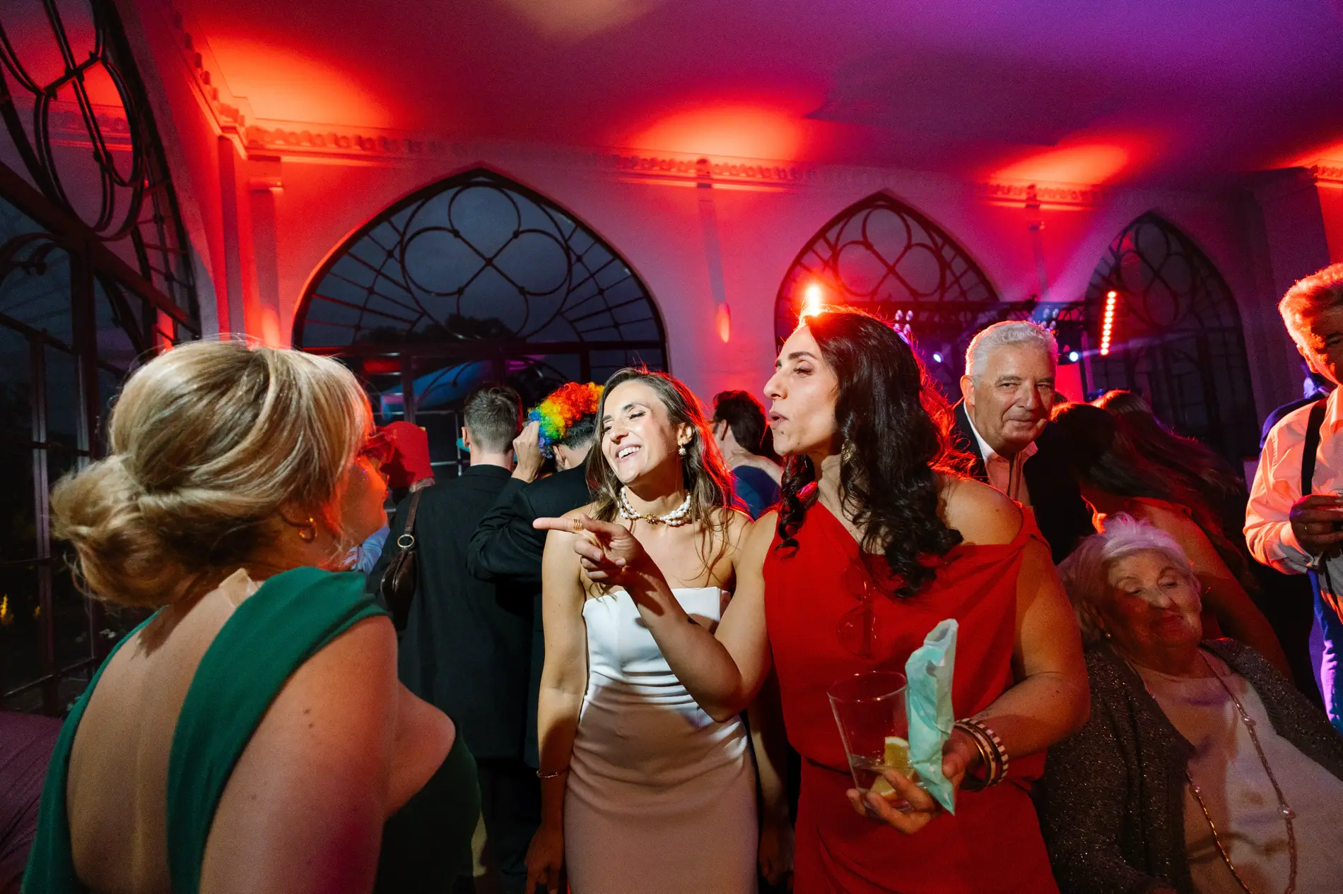 Invitadas bailan en el salón iluminado de rojo, en Casa Colorada, Badajoz