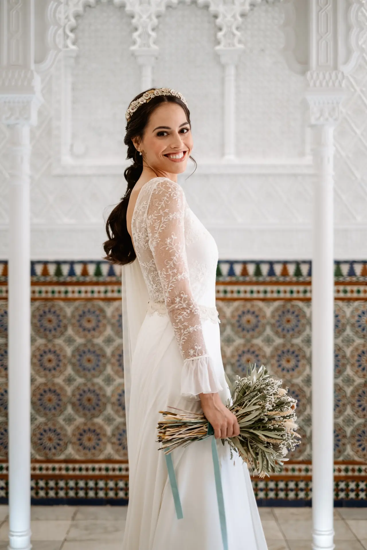 La novia con su ramo junto a un zócalo de azulejos, en Mérida