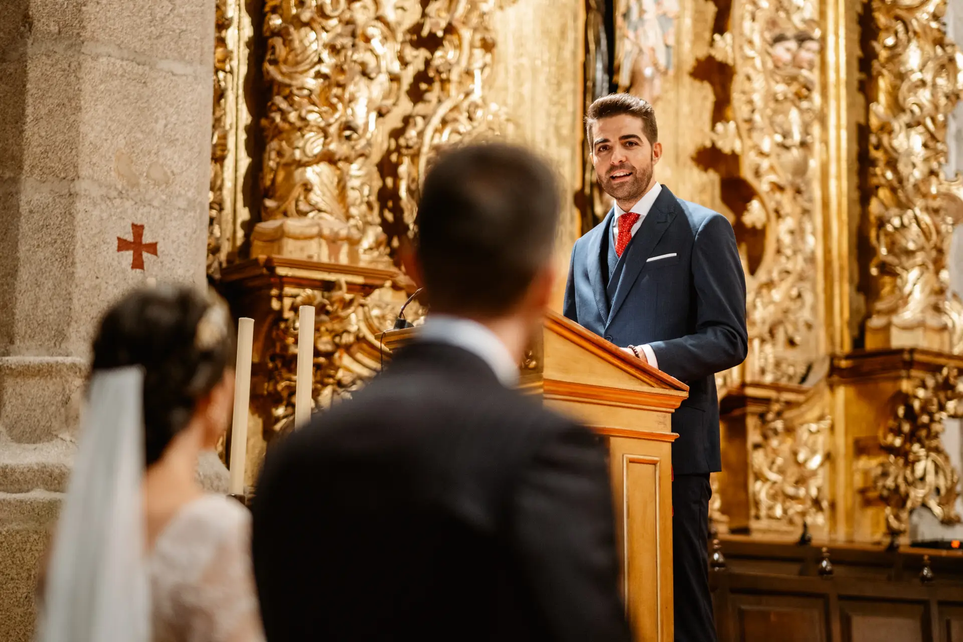 Un invitado lee en el ambón junto al retablo dorado, en Mérida