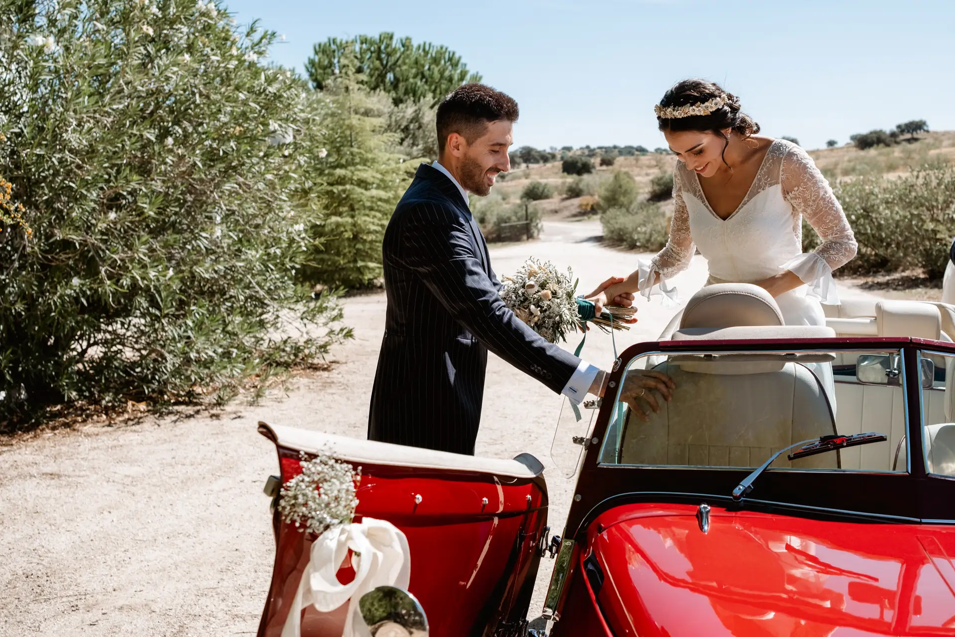 Los novios junto al descapotable rojo en un camino de tierra, en Mérida