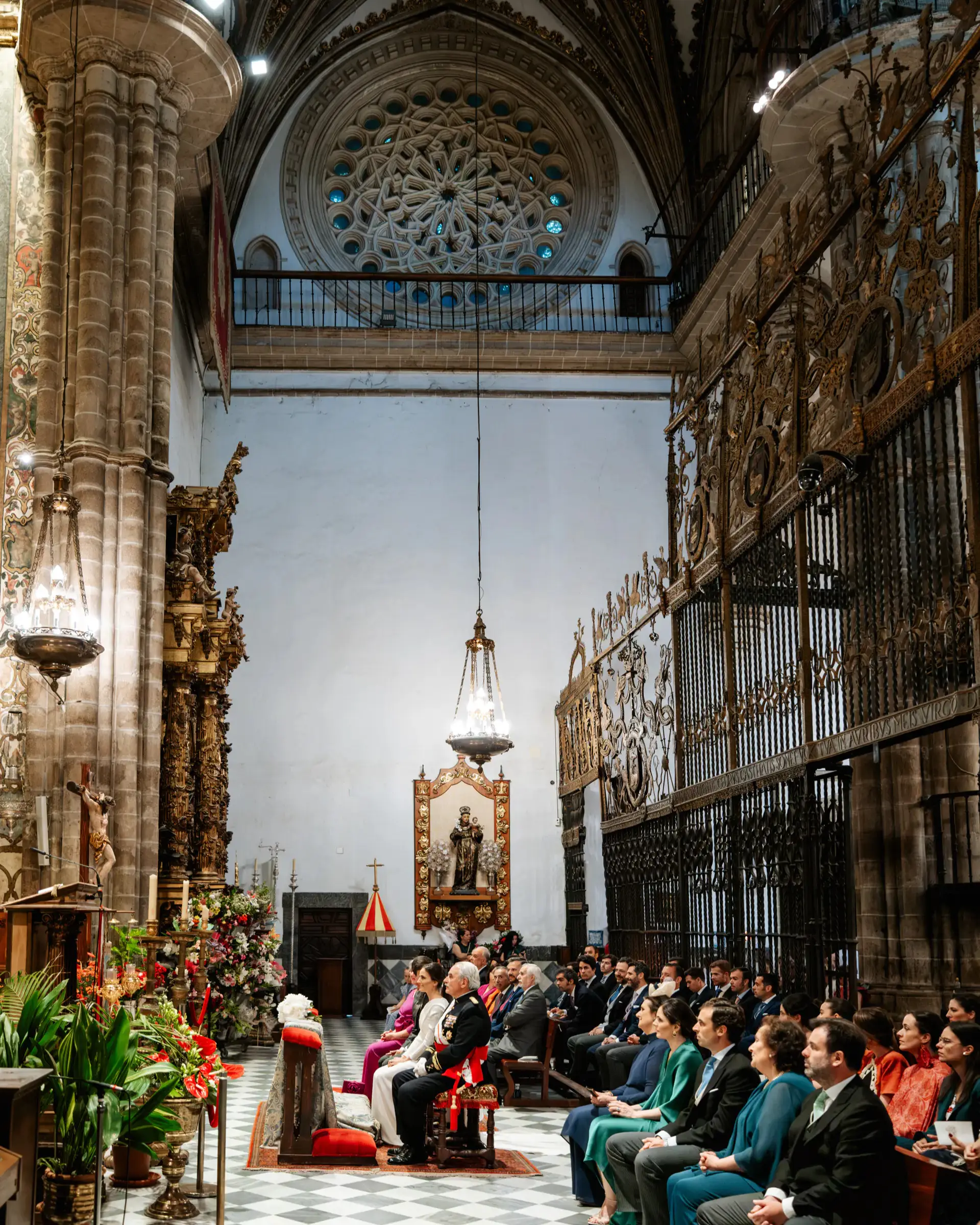 Ceremonia en una iglesia con rejas doradas y rosetón gótico