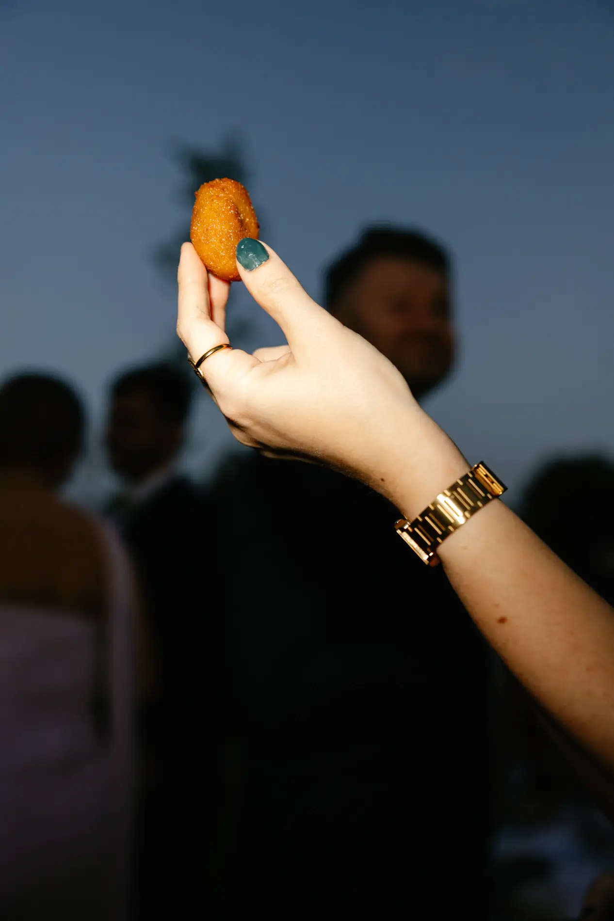Una invitada sostiene una croqueta durante el cóctel al anochecer, en Badajoz