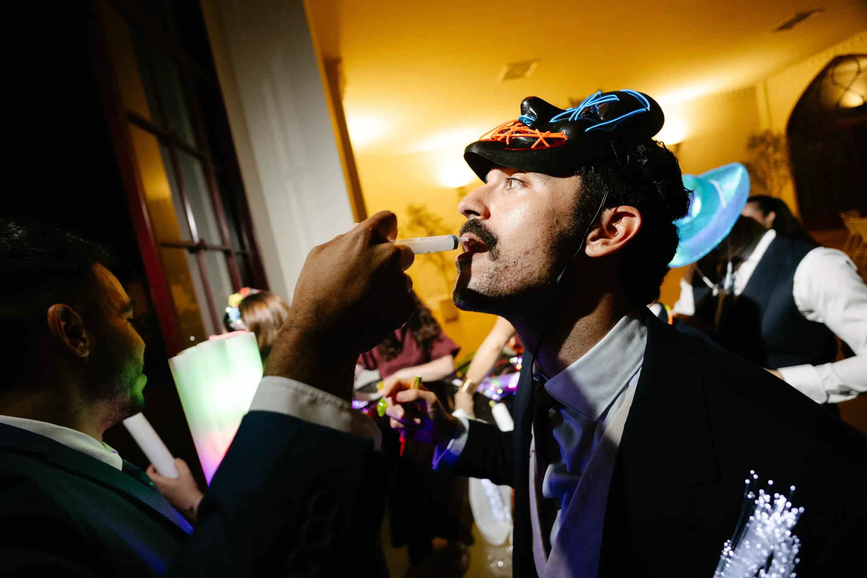 Un invitado con gorra luminosa bebe durante la fiesta, en Badajoz
