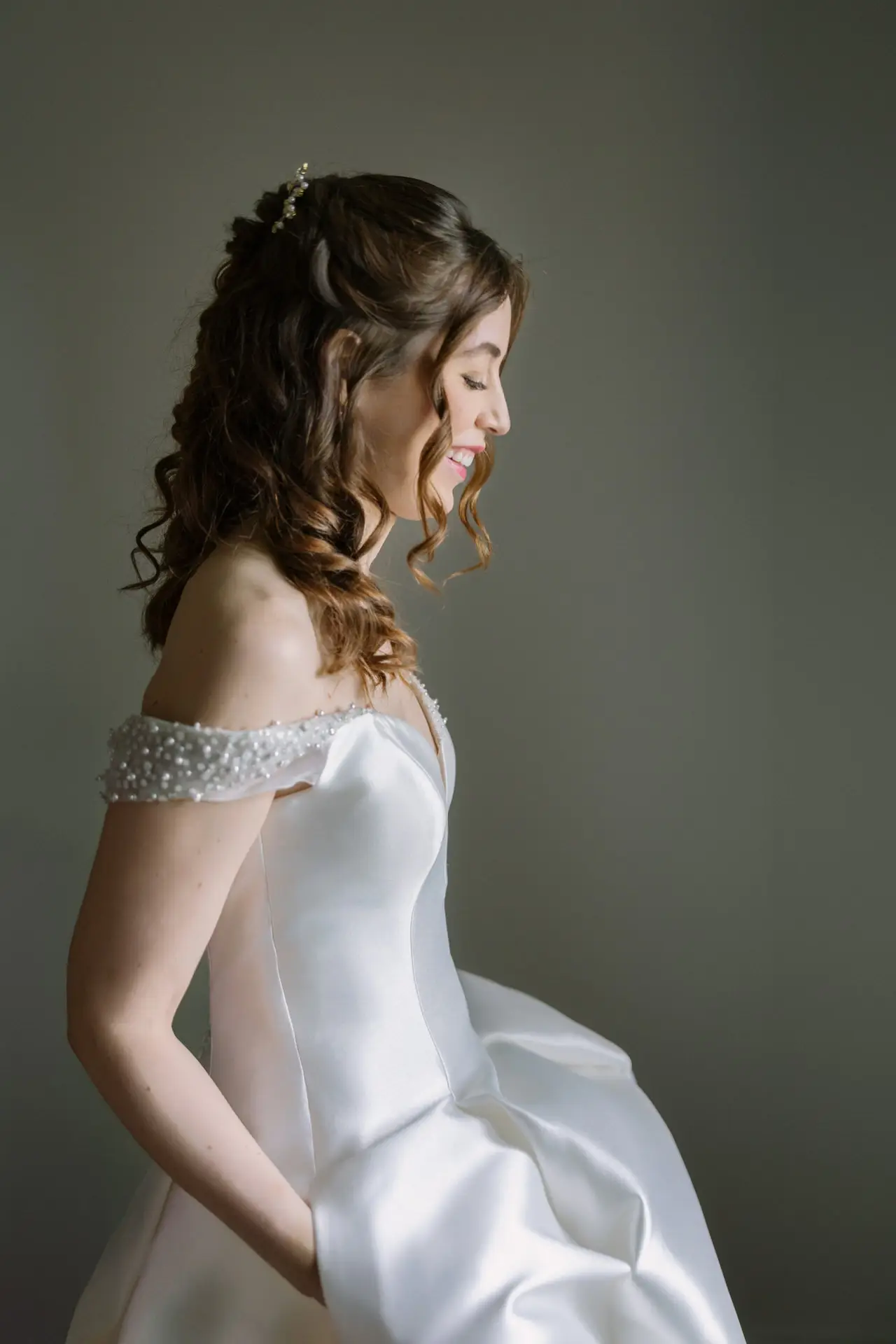 Novia de perfil con vestido de hombros de perlas