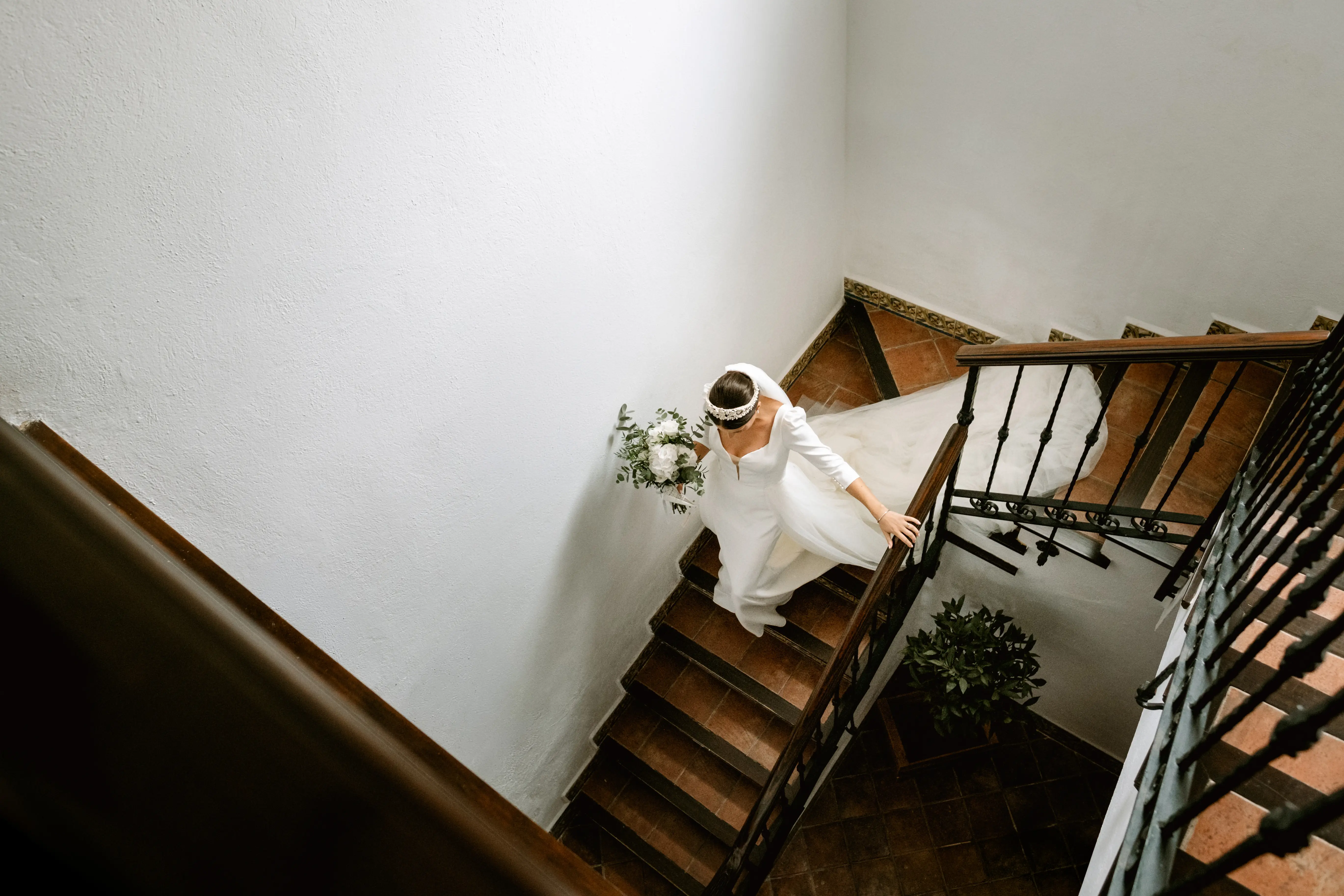 La novia sube una escalera con su ramo vista desde arriba