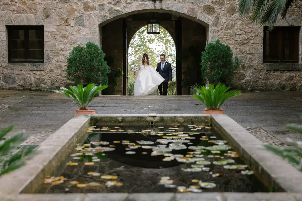 Los novios bajo un arco de piedra junto a un estanque