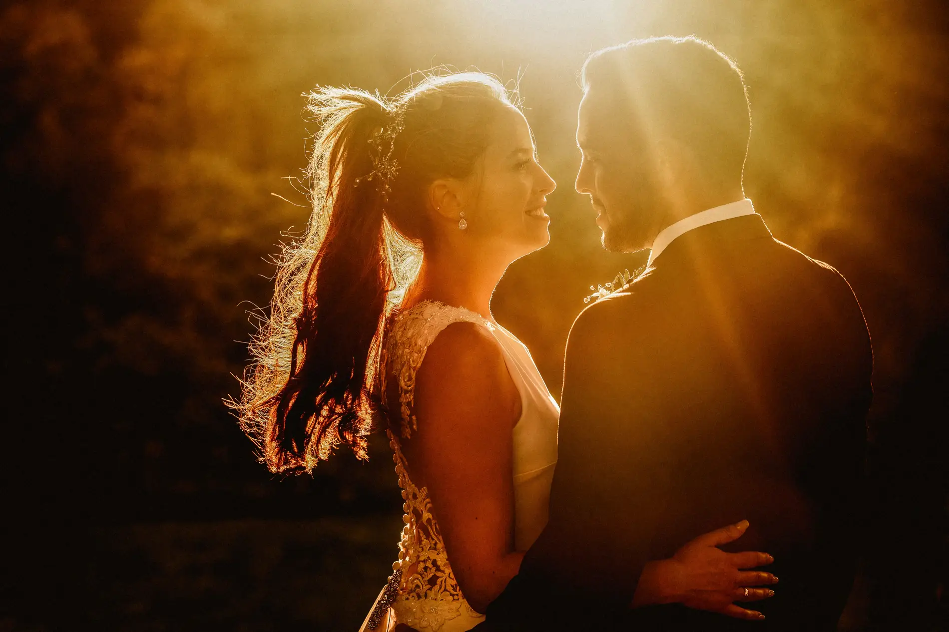 Los novios se miran a contraluz al atardecer