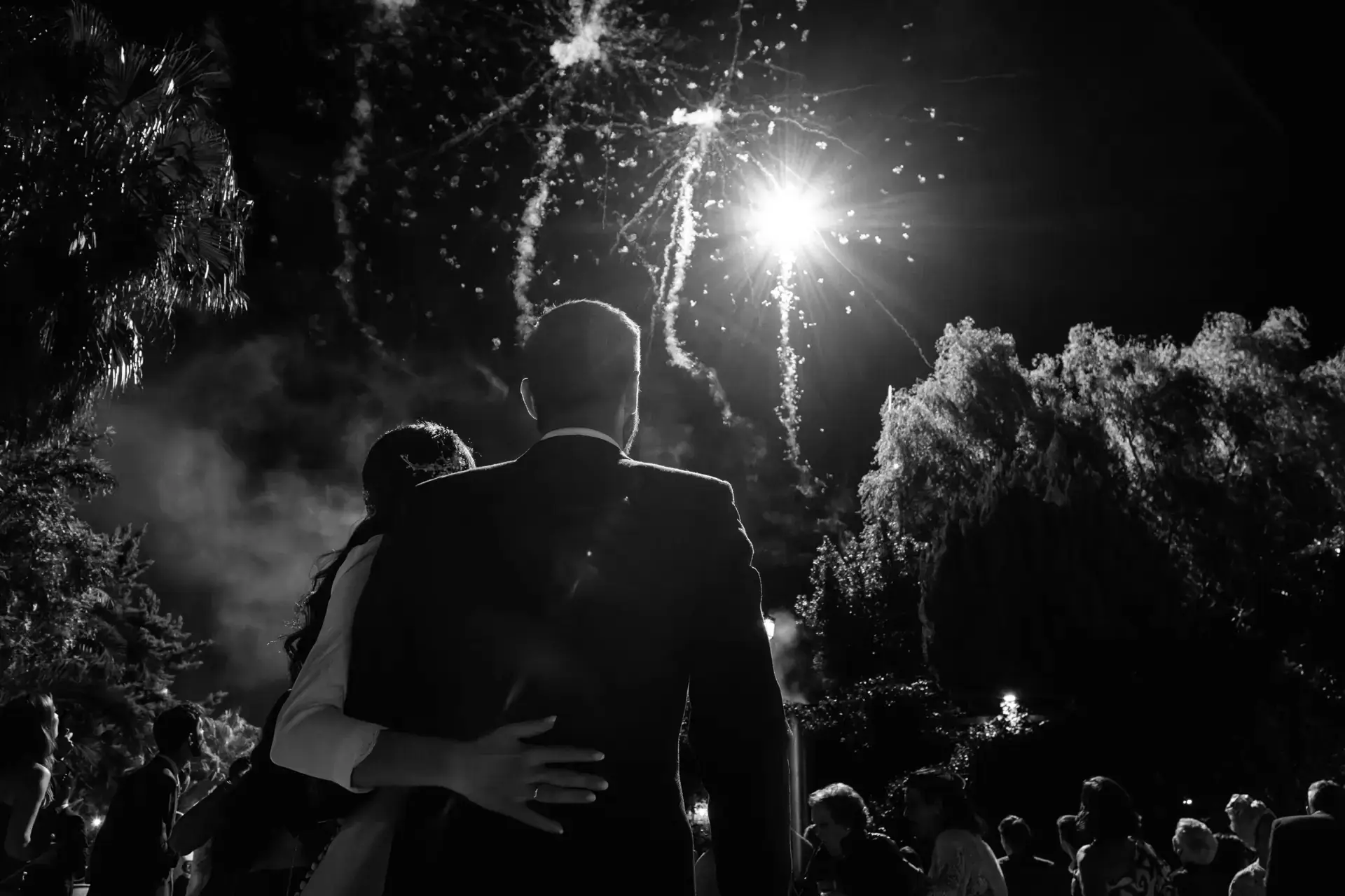 Los novios abrazados bajo fuegos artificiales, en blanco y negro