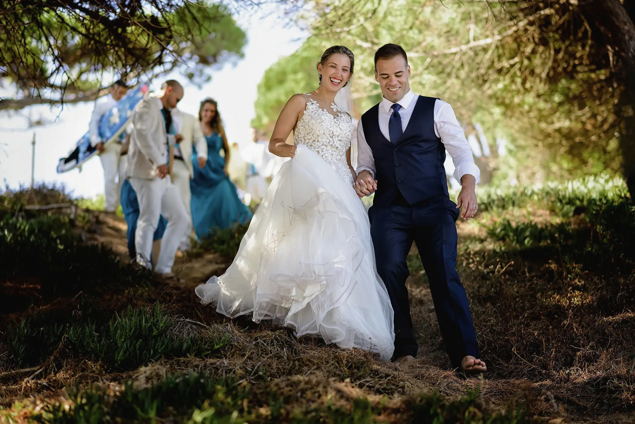 Los novios pasean con sus invitados por un camino de pinos
