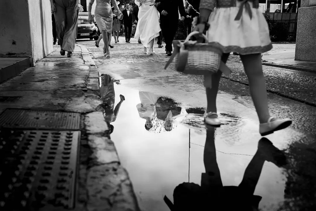 Los novios reflejados en un charco de la calle, en blanco y negro
