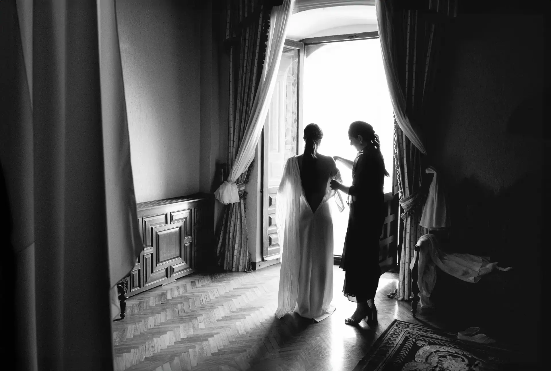 La novia se prepara junto a una ventana, en blanco y negro