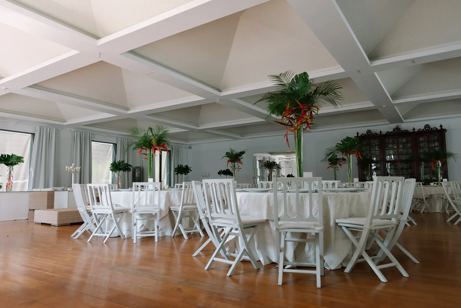 Salón del banquete con sillas blancas y flores tropicales, en la Quinta da Grila, Lisboa