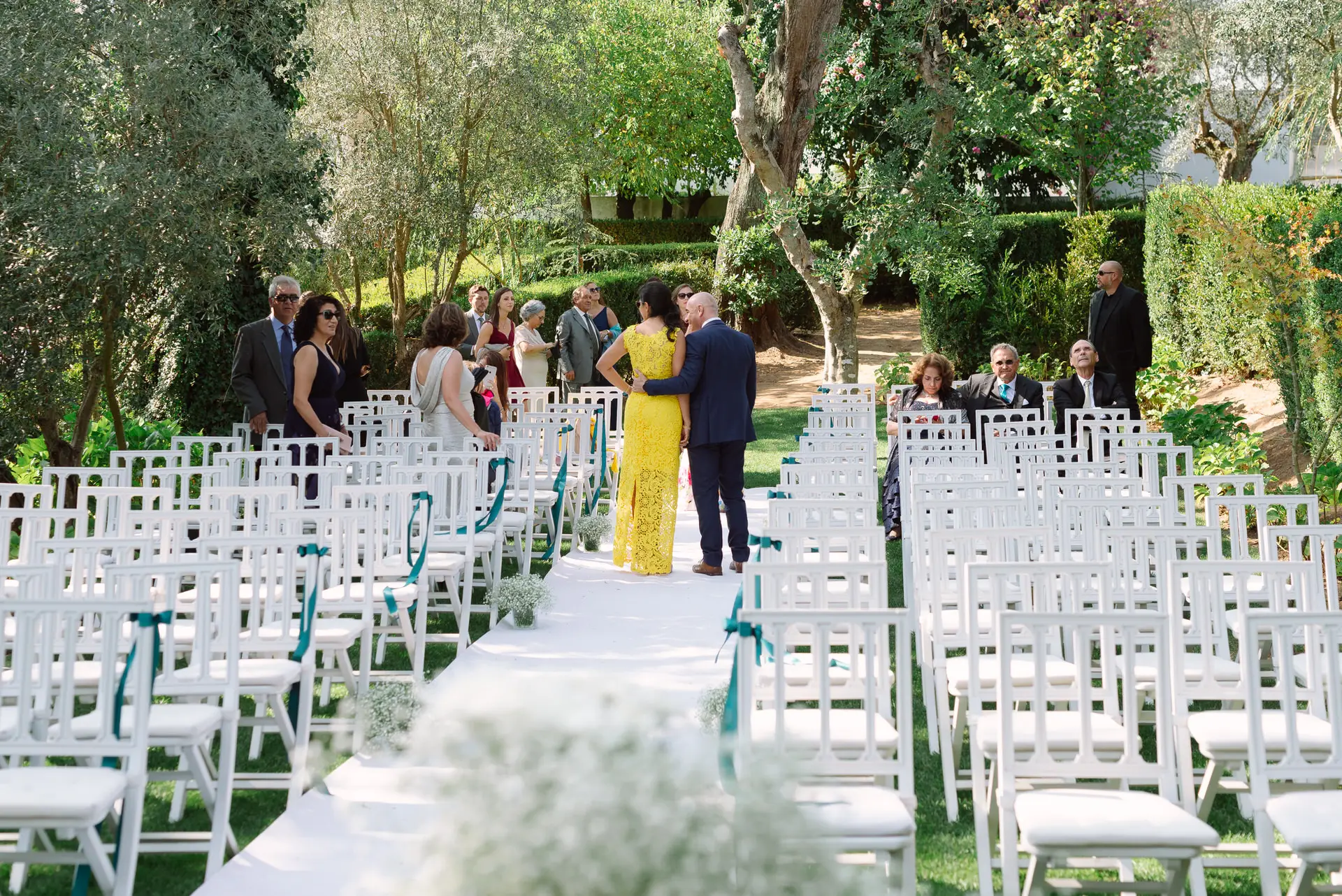 Invitados llegan a la ceremonia entre sillas blancas en el jardín, en la Quinta da Grila, Lisboa