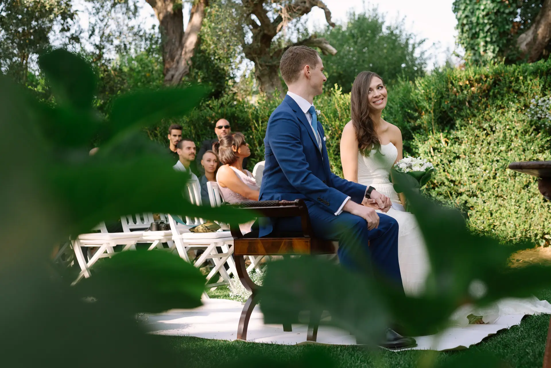 Alana y Quinn sentados en la ceremonia, vistos entre hojas, en la Quinta da Grila, Lisboa