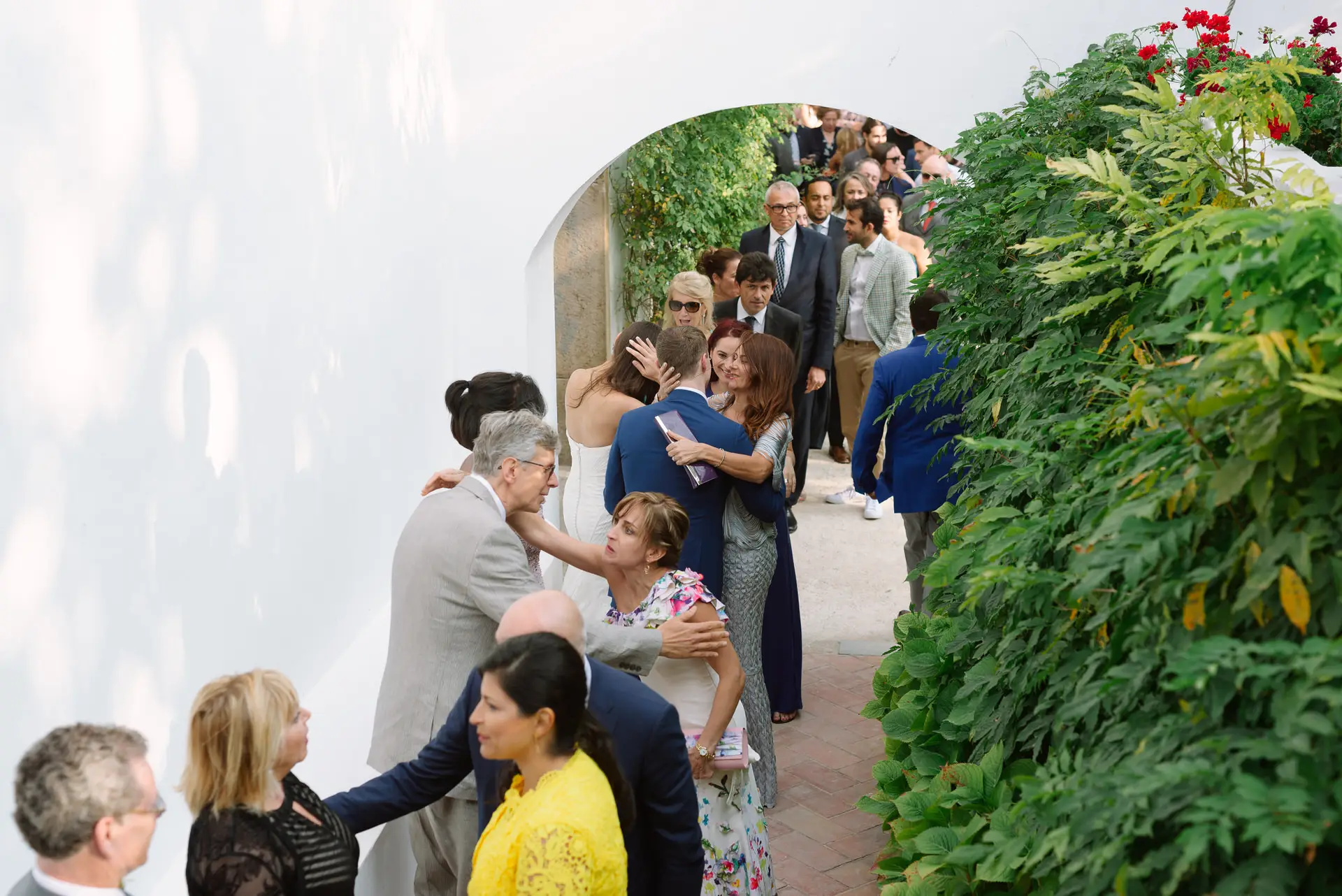 Invitados se saludan bajo un arco blanco cubierto de plantas, en la Quinta da Grila, Lisboa