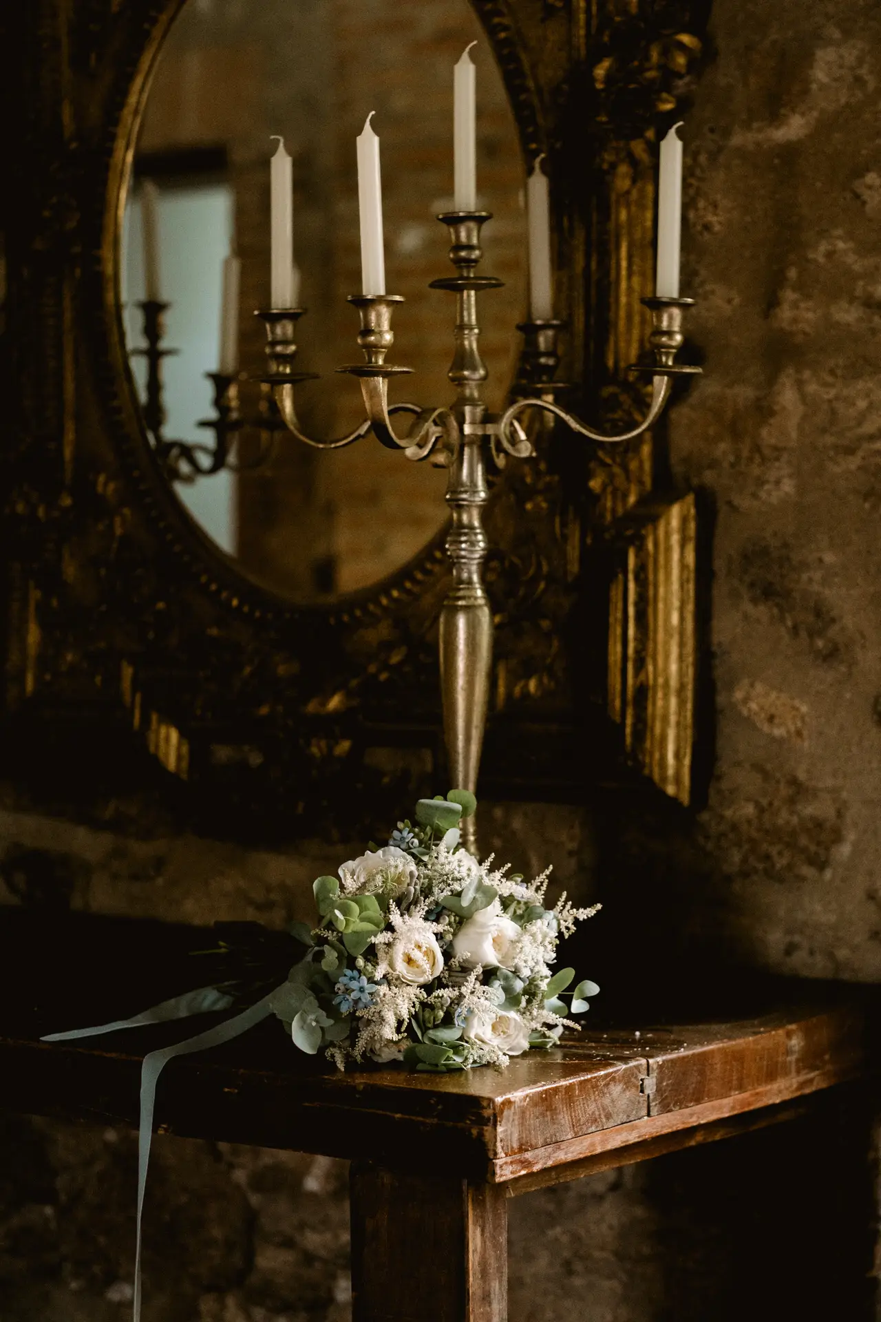 Ramo de novia junto a un candelabro y un espejo antiguo