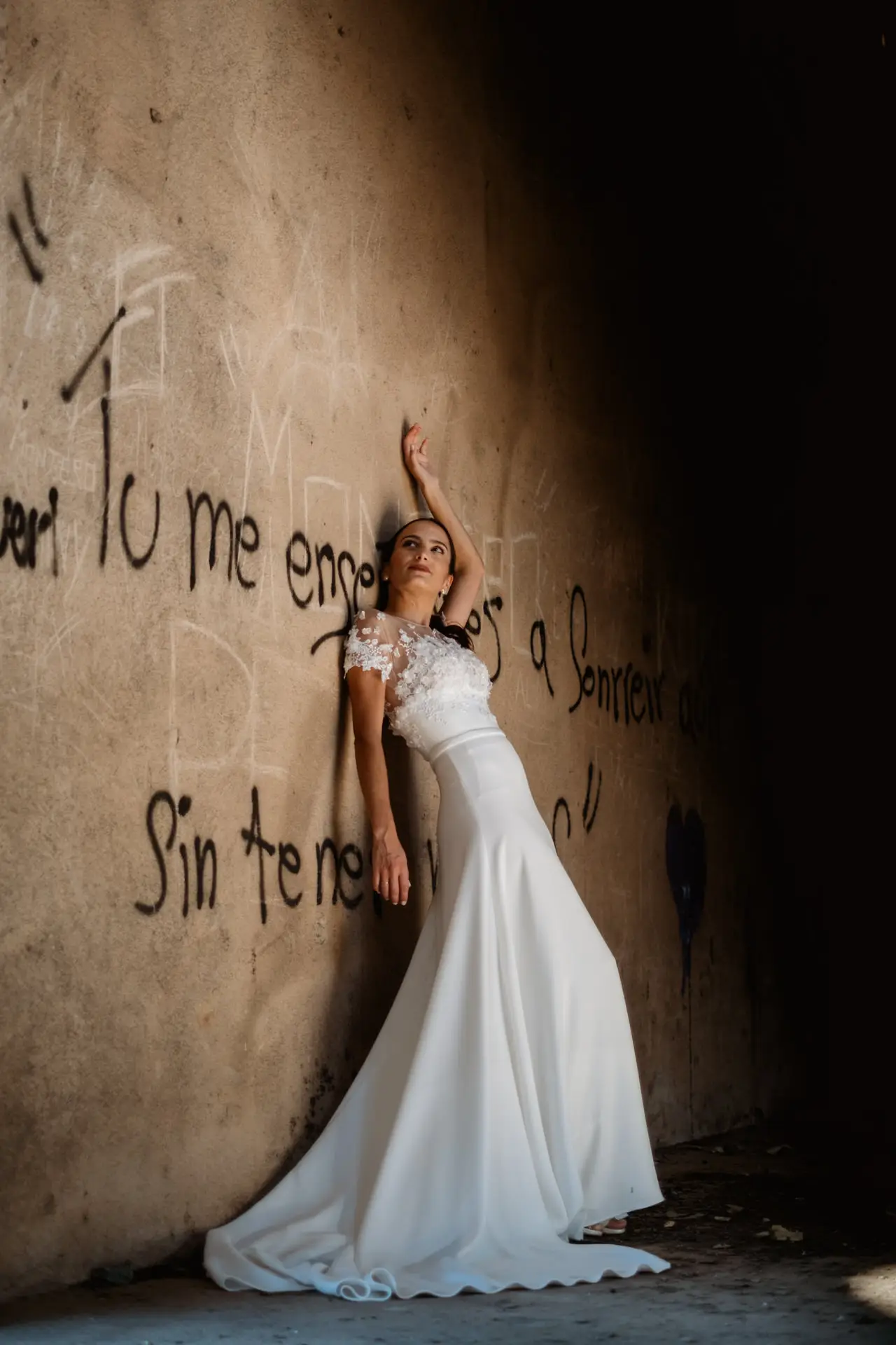 Rocío apoyada en una pared con una pintada, en su postboda