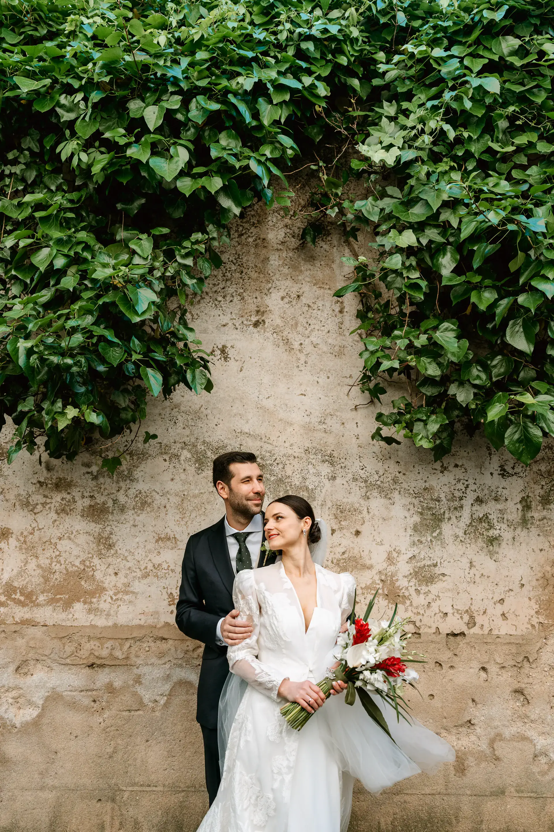 Los novios junto a un muro de hiedra en la ciudad monumental de Cáceres