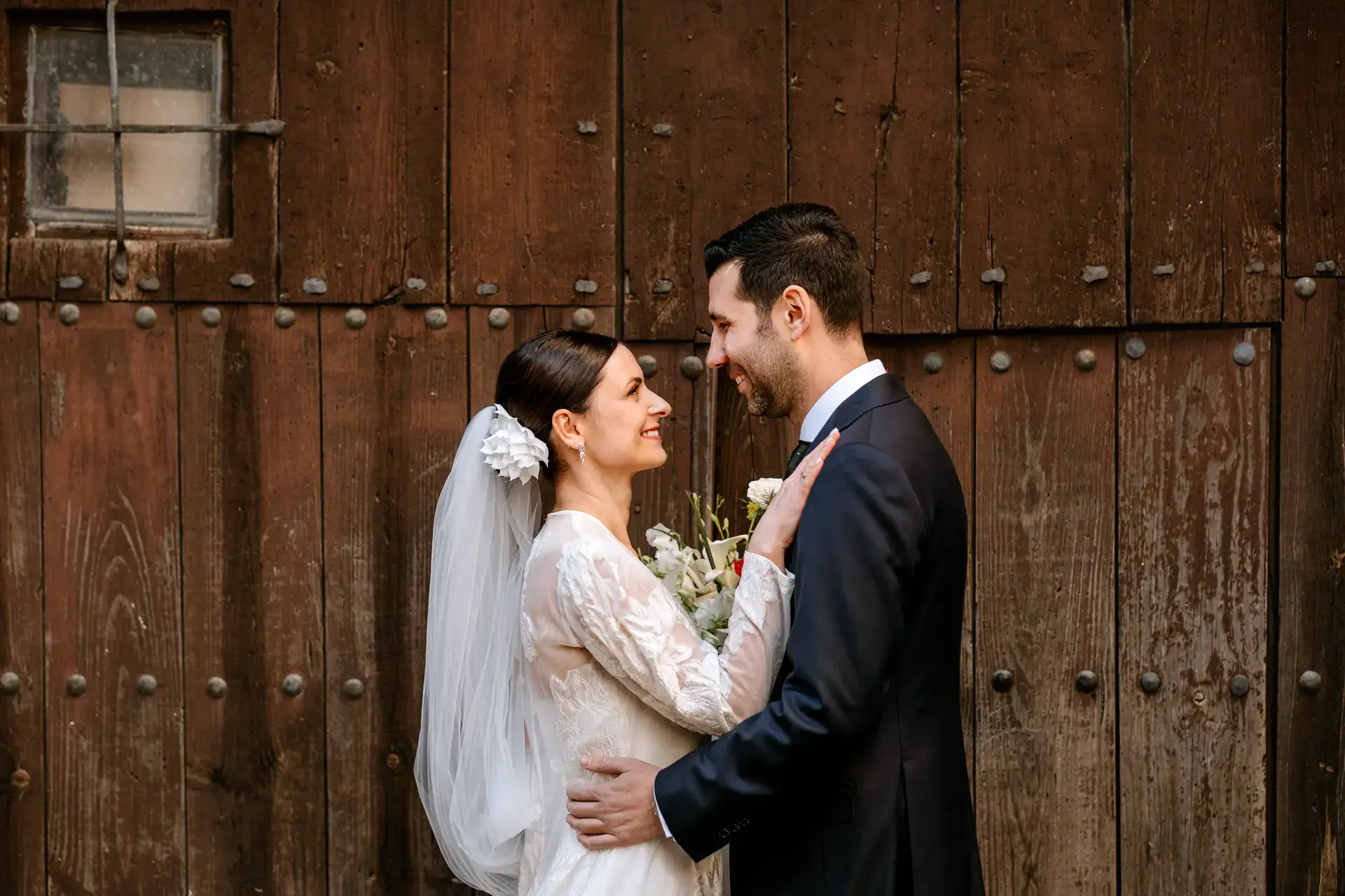 Los novios abrazados ante una puerta de madera en la ciudad monumental, en Cáceres