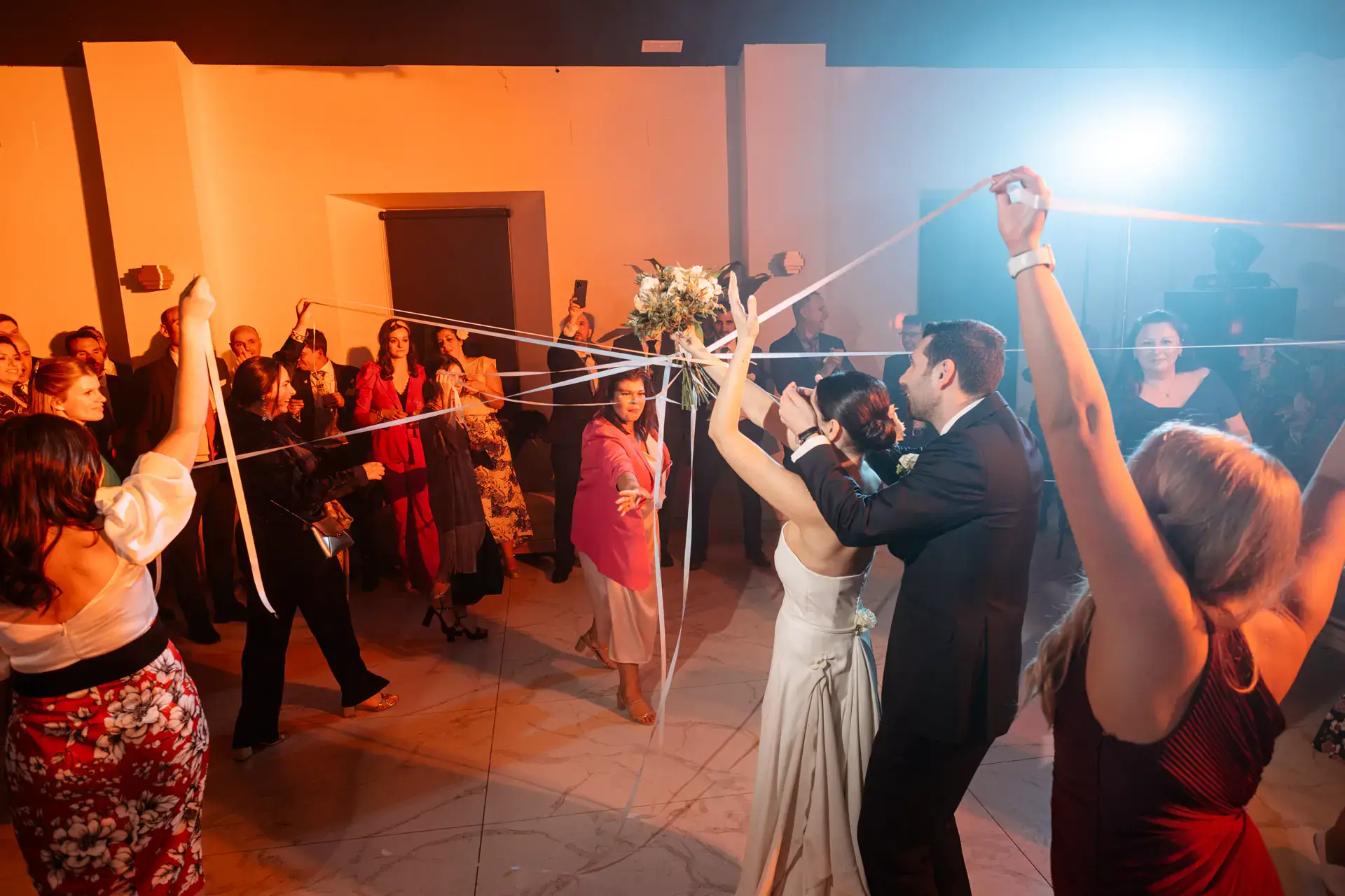 Los novios bailan entre invitados que sujetan las cintas del ramo, en Cáceres