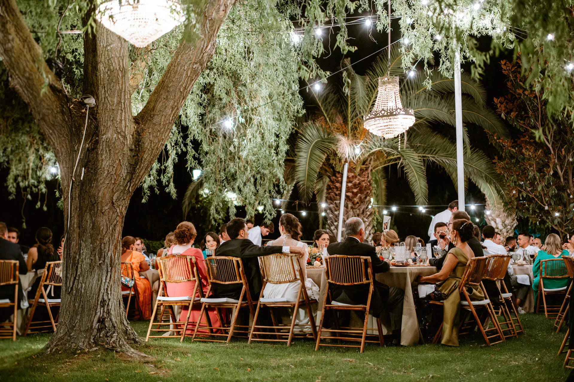Cena al aire libre bajo un sauce con lámparas de cristal