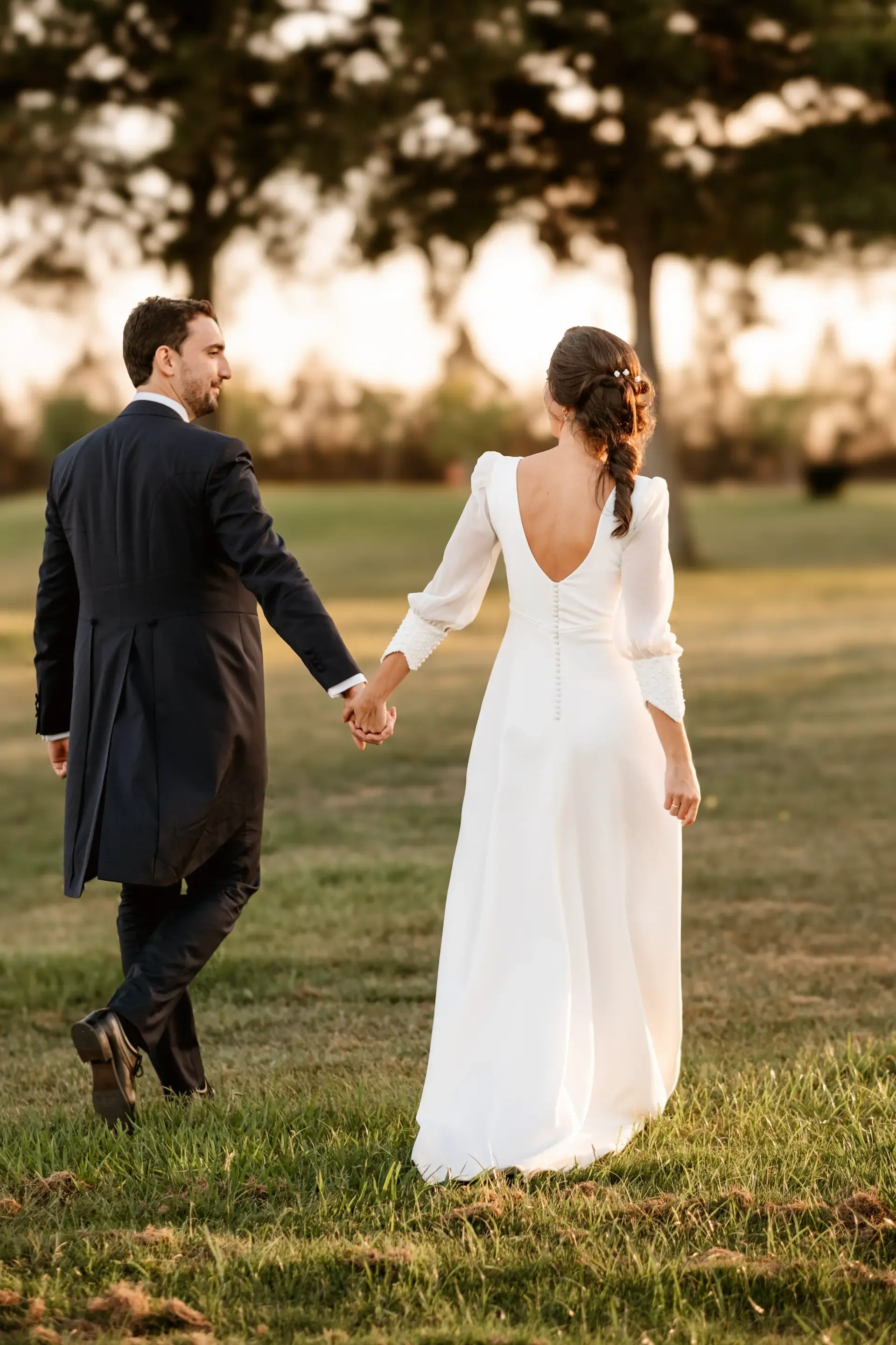 Los novios pasean de la mano al atardecer por los jardines del Golf Guadiana (Badajoz)