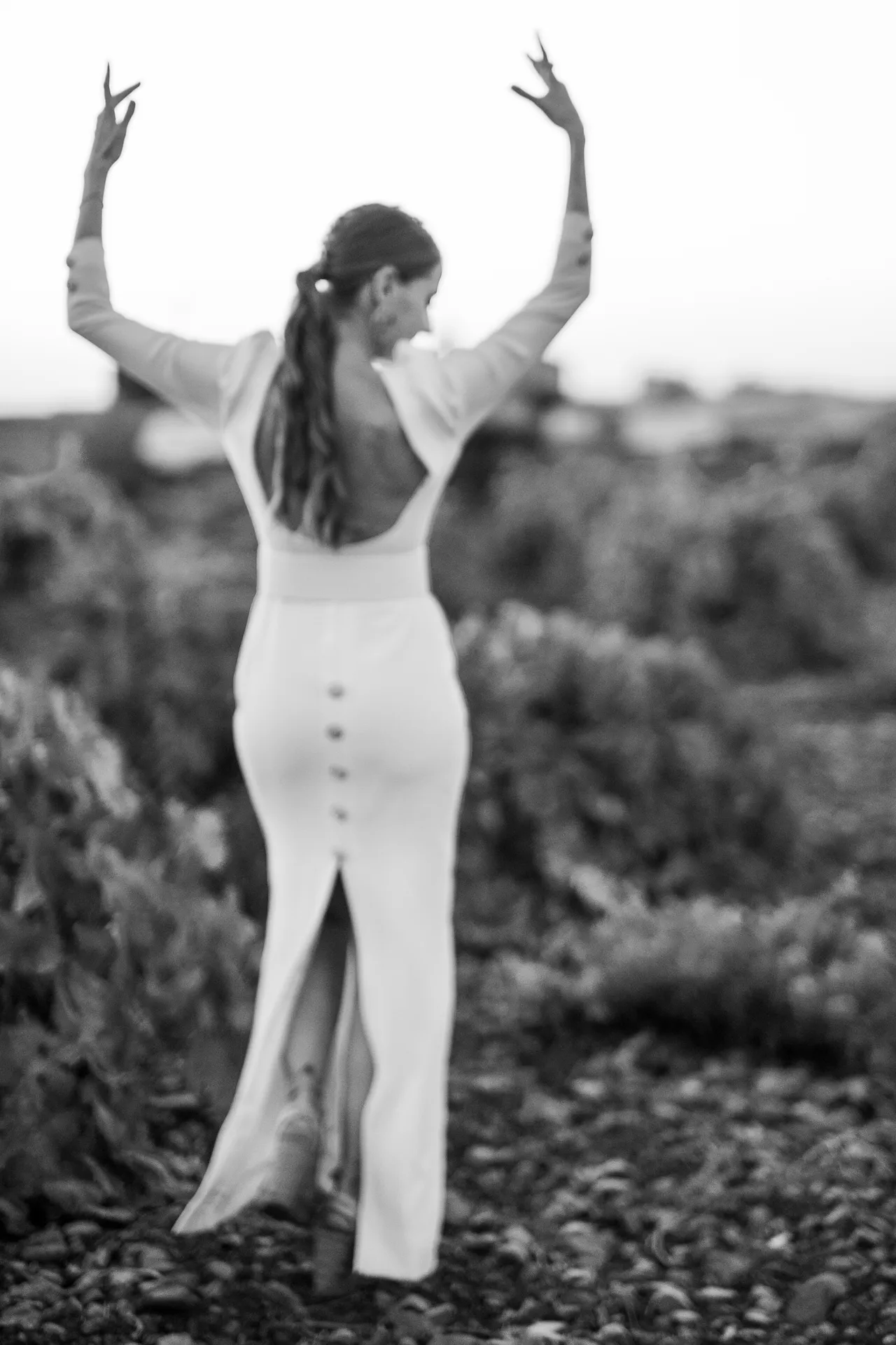 Novia de espaldas bailando con los brazos en alto, en blanco y negro