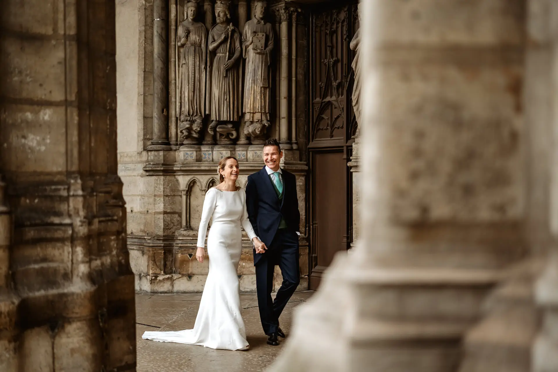 Los novios pasean de la mano junto a una portada gótica en París