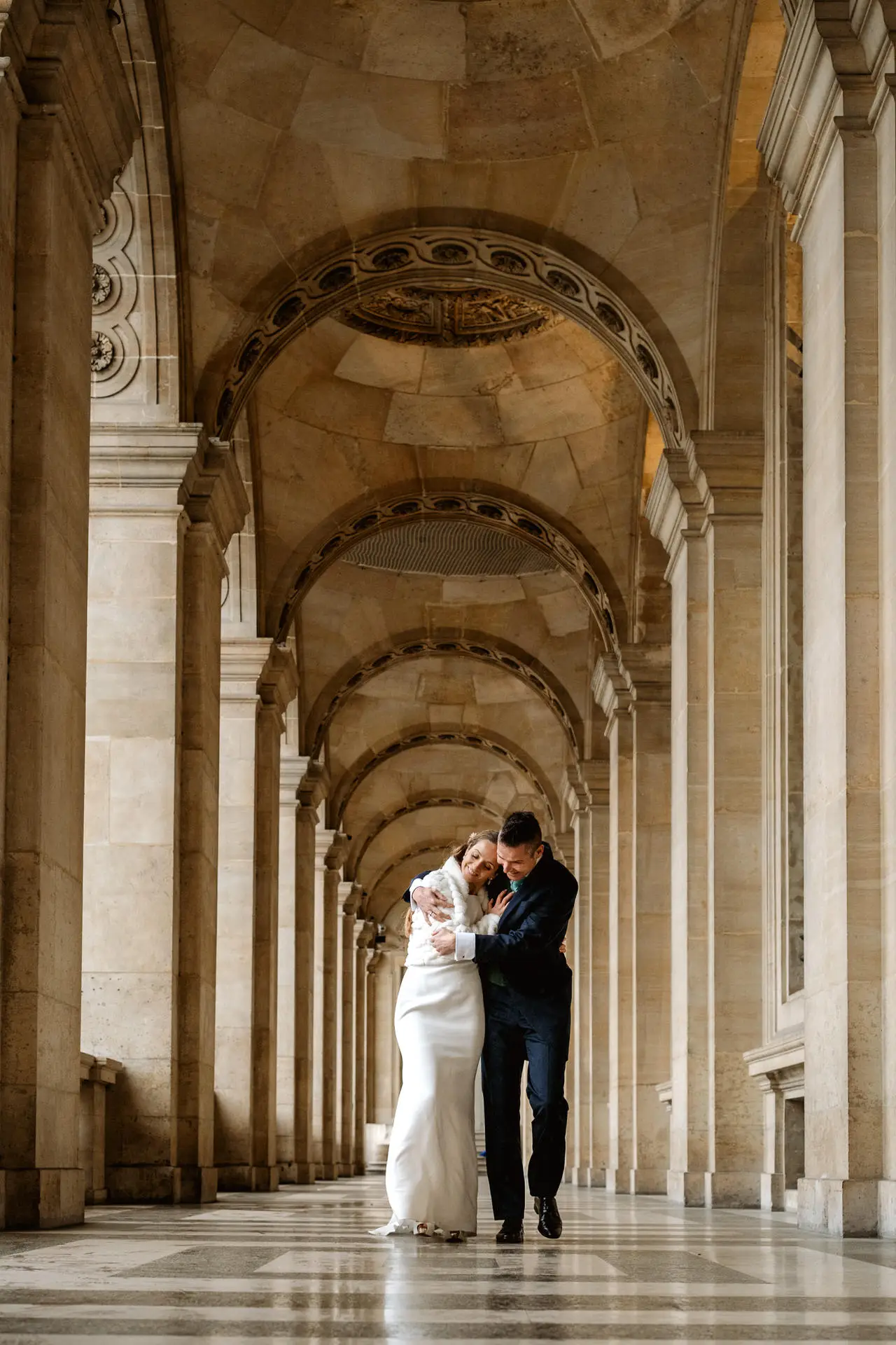 Los novios caminan bajo una galería de arcos en París