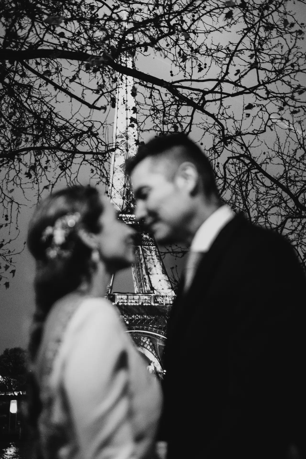 Beso de los novios con la torre Eiffel detrás, en blanco y negro