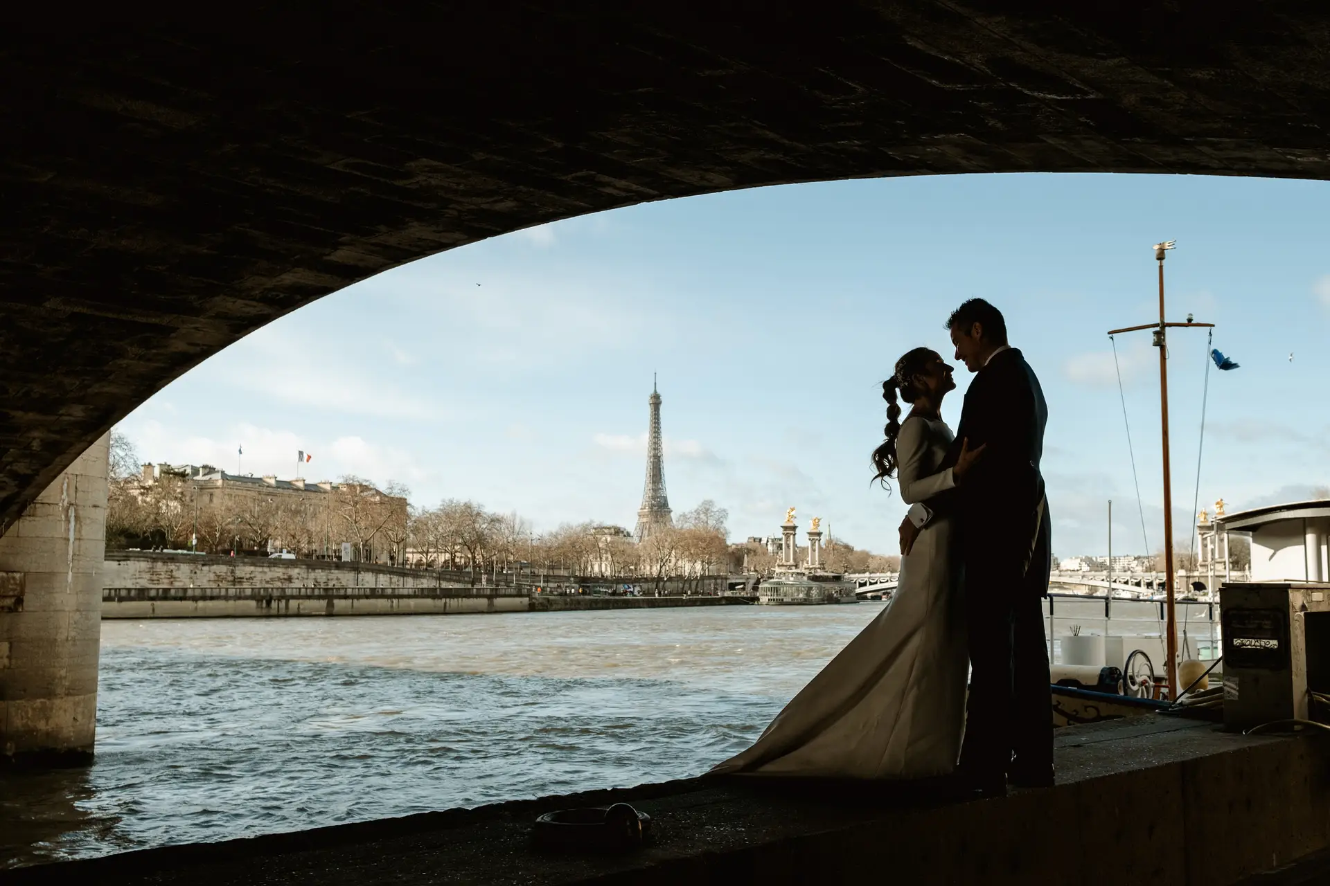 Los novios a contraluz bajo un puente del Sena con la torre Eiffel