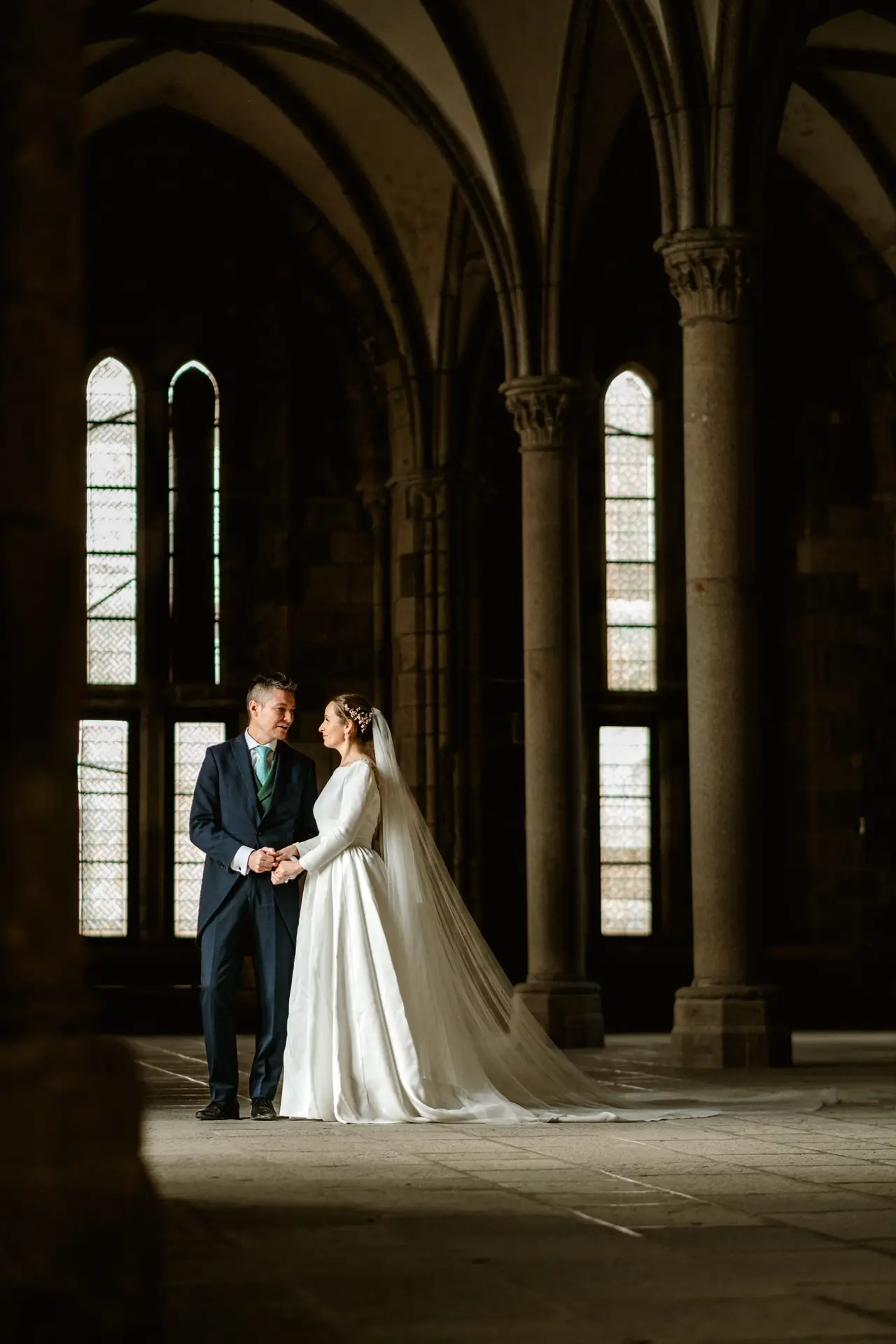Los novios de la mano en una sala gótica de la abadía del Mont Saint-Michel