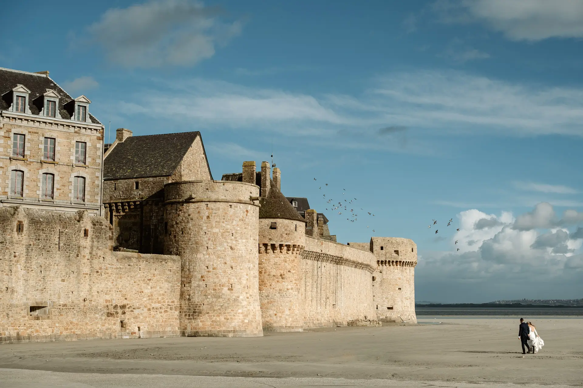 Los novios caminan por la playa ante las murallas del Mont Saint-Michel