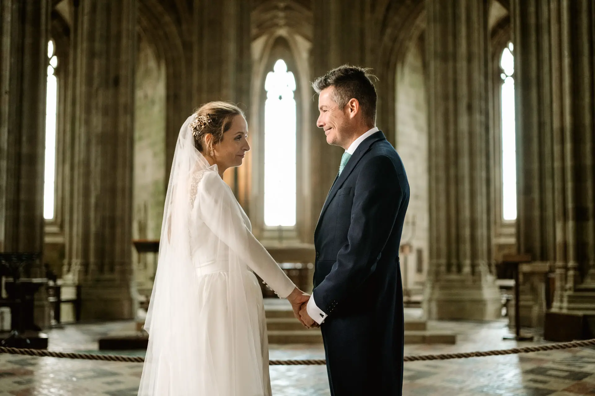 Los novios de la mano en la iglesia gótica de la abadía, en su postboda en Francia