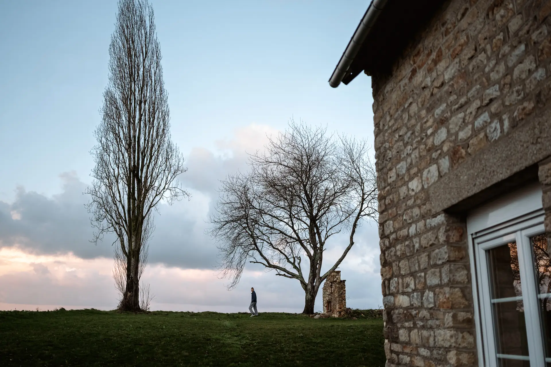 Árboles y casa de piedra al atardecer en Normandía