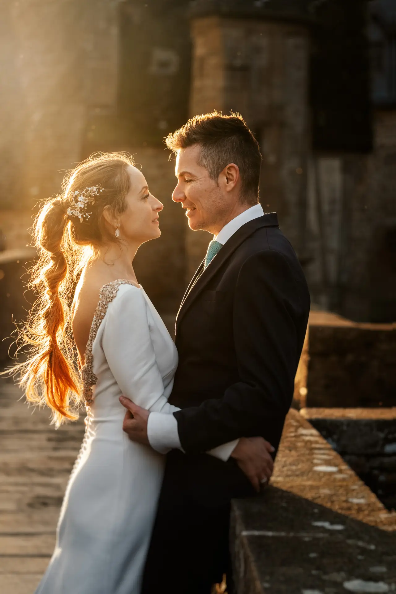 Los novios se miran al atardecer en la muralla, en su postboda en Francia