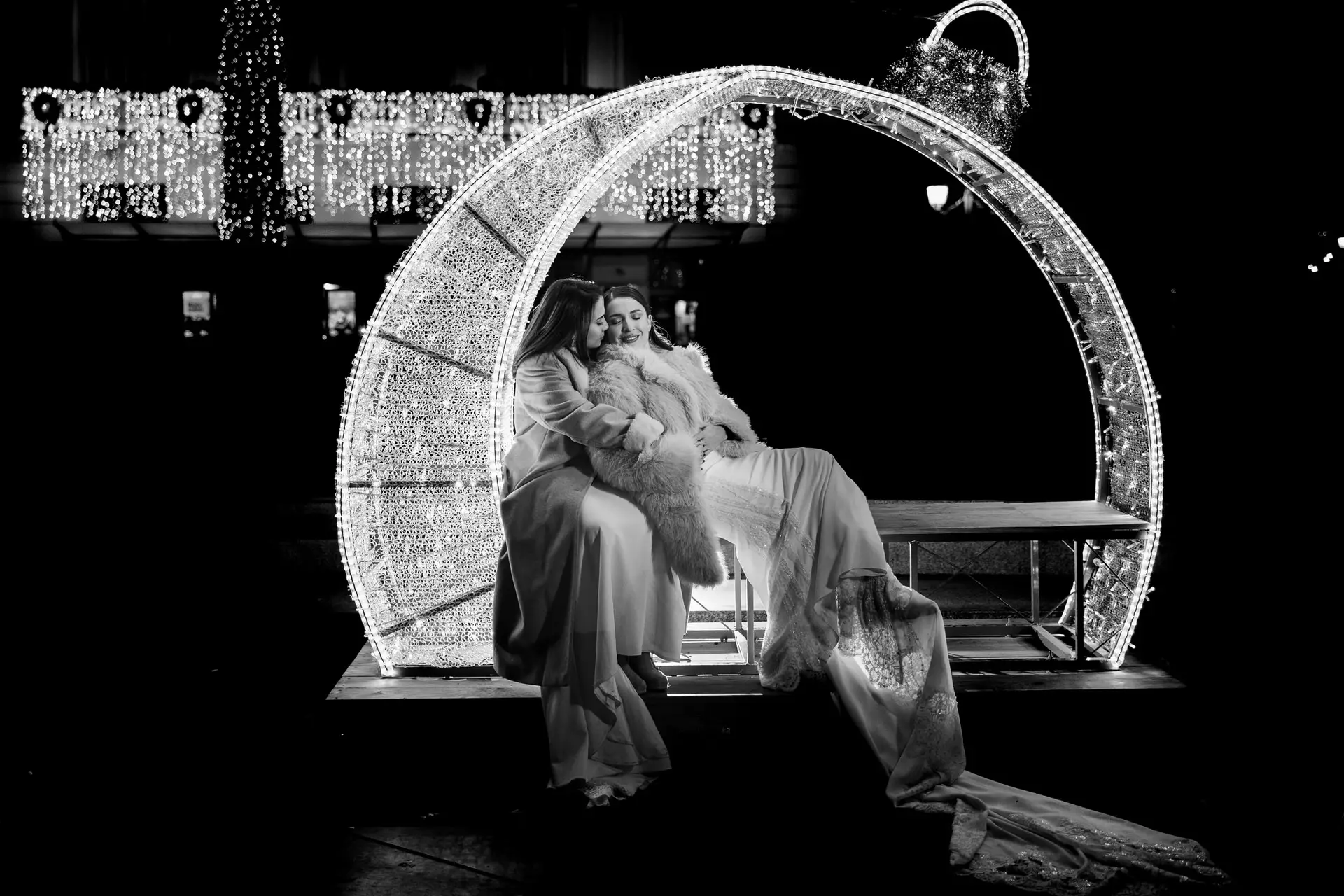 Rocío y Nines sentadas en un adorno luminoso de Navidad, en blanco y negro, en Badajoz