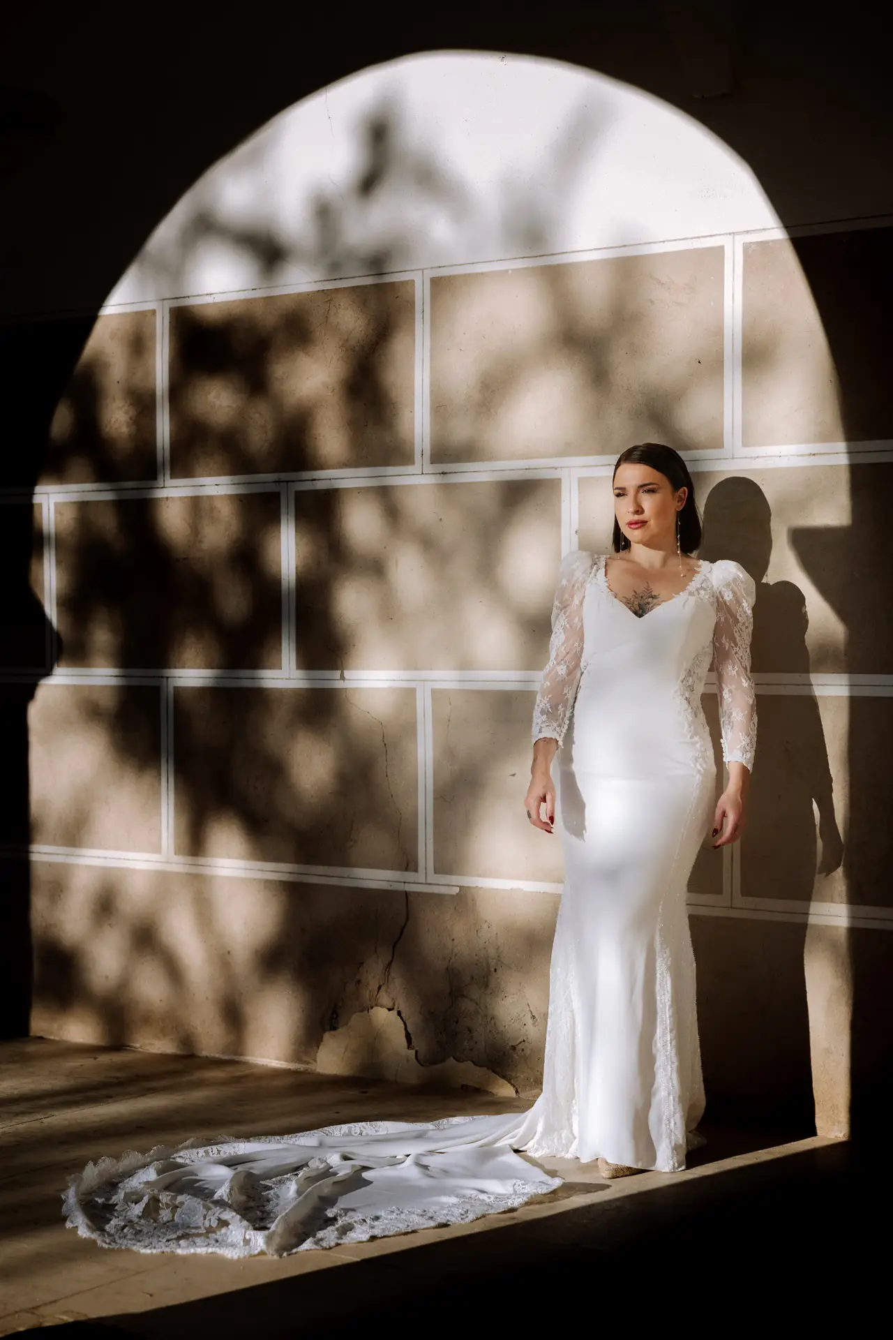 Una de las novias en un arco con sombras de hojas, en Badajoz
