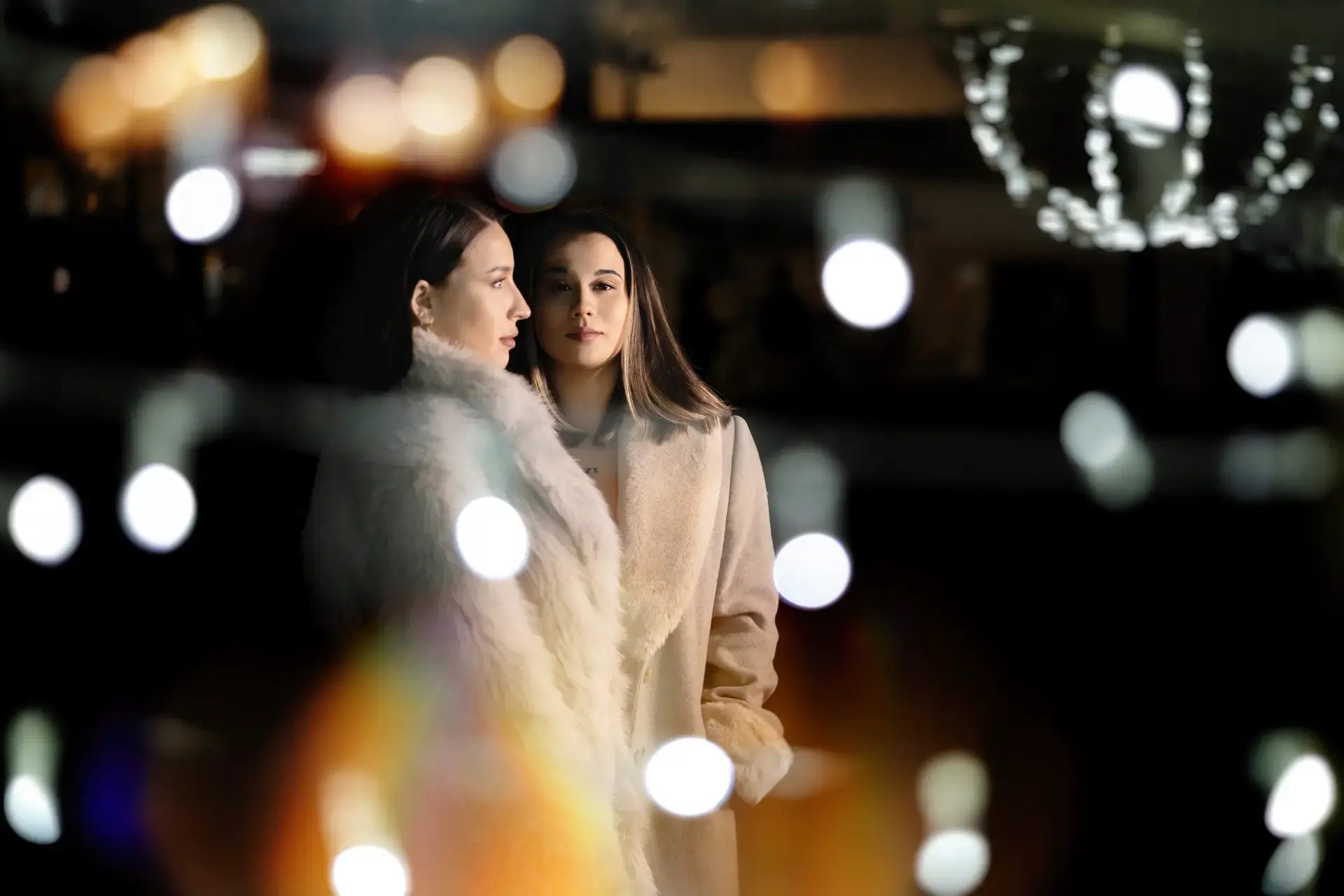 Dos novias con abrigos de pelo entre luces navideñas