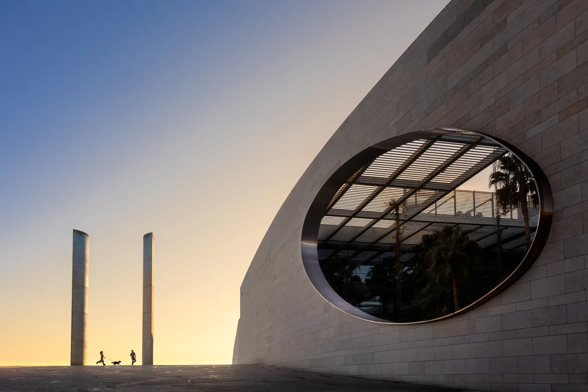 Los novios a lo lejos junto a un edificio moderno al atardecer