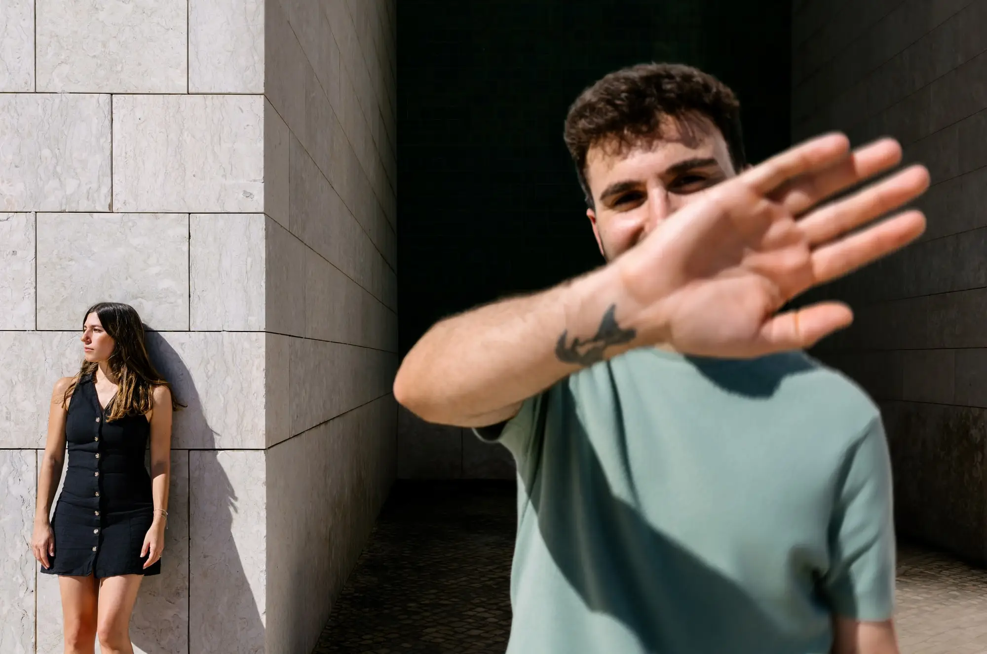 Marina apoyada en una pared mientras Juan Antonio tapa el objetivo con la mano, en Lisboa