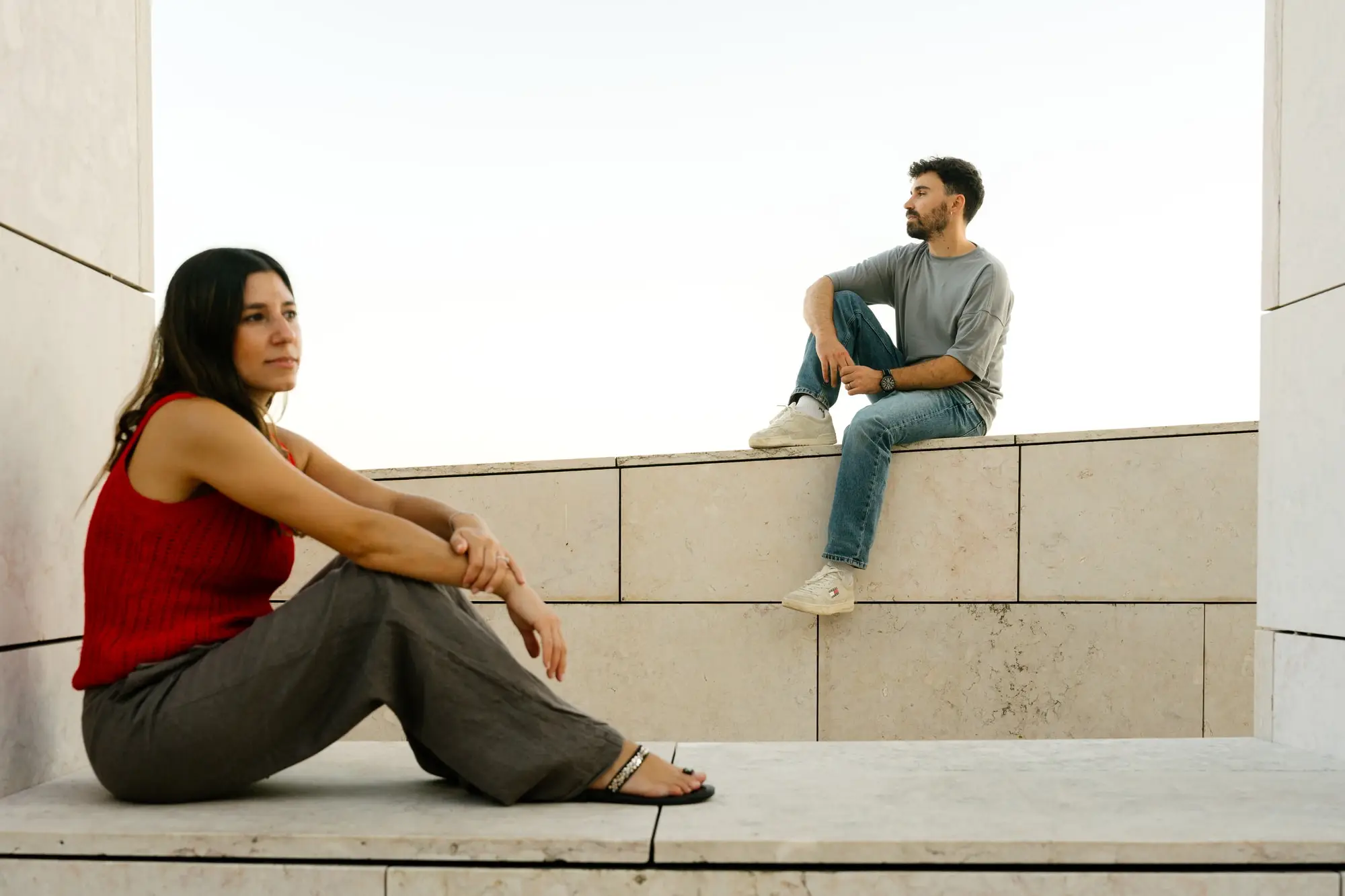 Marina sentada en el suelo y Juan Antonio sobre un muro, entre paredes blancas, en Lisboa