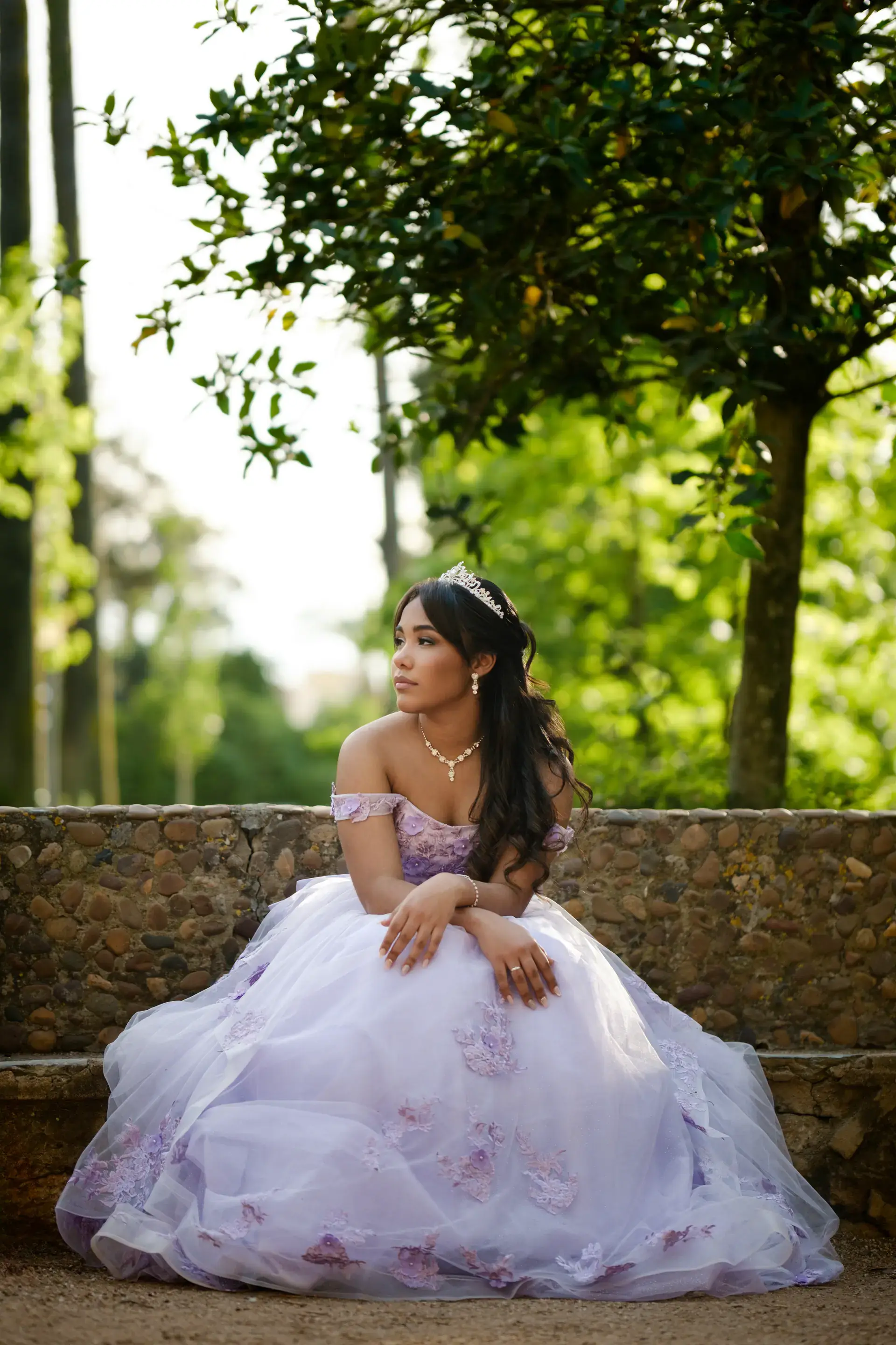 Quinceañera con vestido lila sentada en un jardín